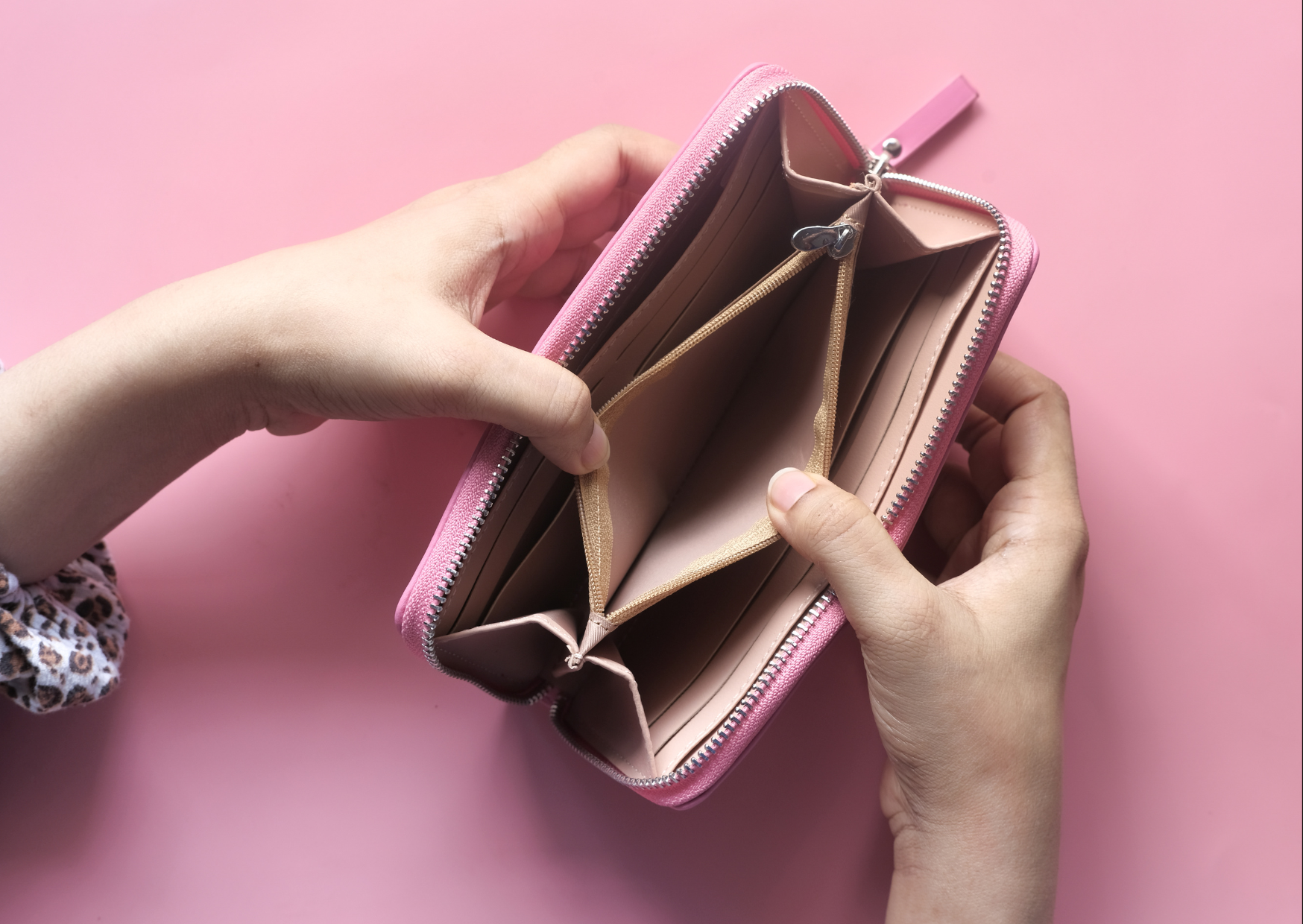 hands opening pink wallet in pink background